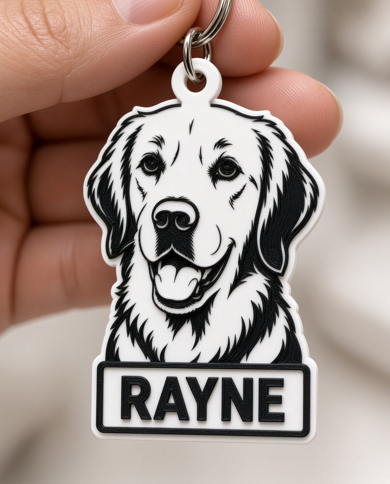 Rayne portrait keychain held in a hand, showing its printed layers and personalized nameplate